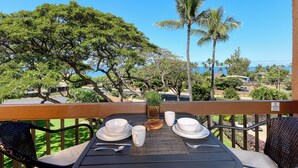 A table set for dining with a view of the ocean and palm trees.