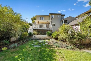A residential property with a two-story house, a front porch, and a landscaped garden with a stone pathway.