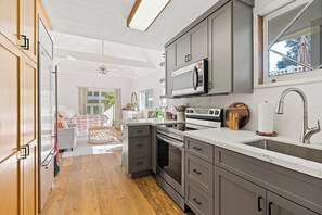 A modern kitchen with grey cabinets, a white countertop, and a stainless steel sink.