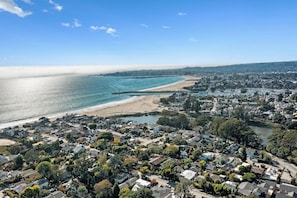 A coastal residential area with houses, a beach, and a pier.