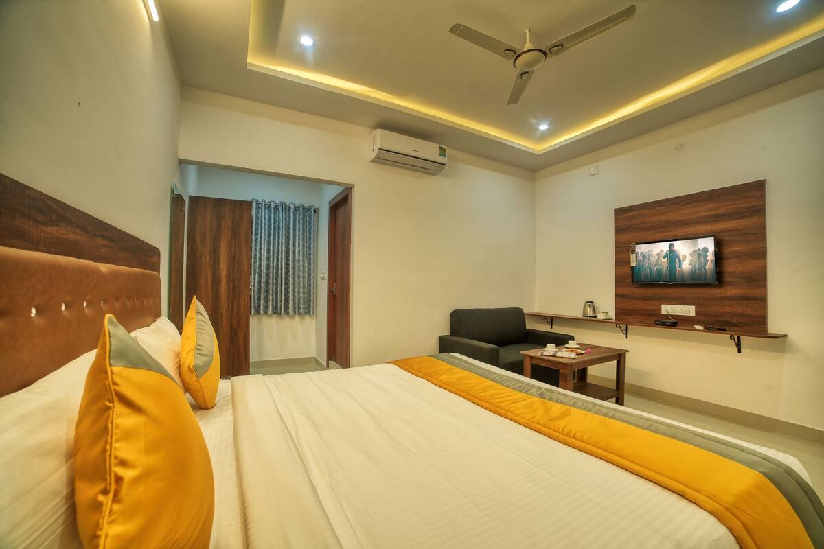 Ein Hotelzimmer mit Bett, Schreibtisch, Stuhl, Fernseher und Klimaanlage.