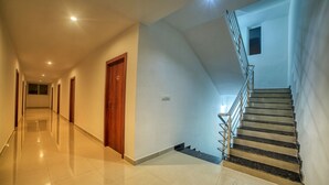 A long, well-lit hallway with a staircase on the right. - Visa Inn Bangalore Airport (Bengaluru)