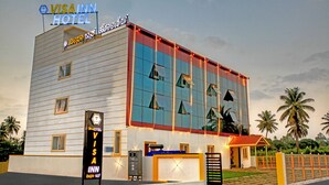 A modern building with a sign reading "VISA INN HOTEL" and a small attached structure with a red roof. - Visa Inn Bangalore Airport (Bengaluru)