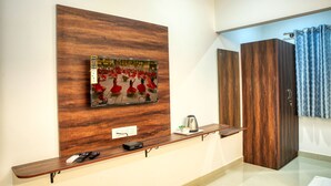 A modern hotel reception area with a wooden panel wall, a mounted artwork, a coffee machine, and a wooden wardrobe. - Visa Inn Bangalore Airport (Bengaluru)