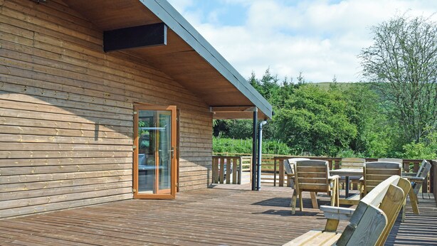 A wooden deck with outdoor furniture, a glass door entrance, and a covered area. - 3 bedroom accommodation in Llandrindod Wells (Llandrindod Wells)