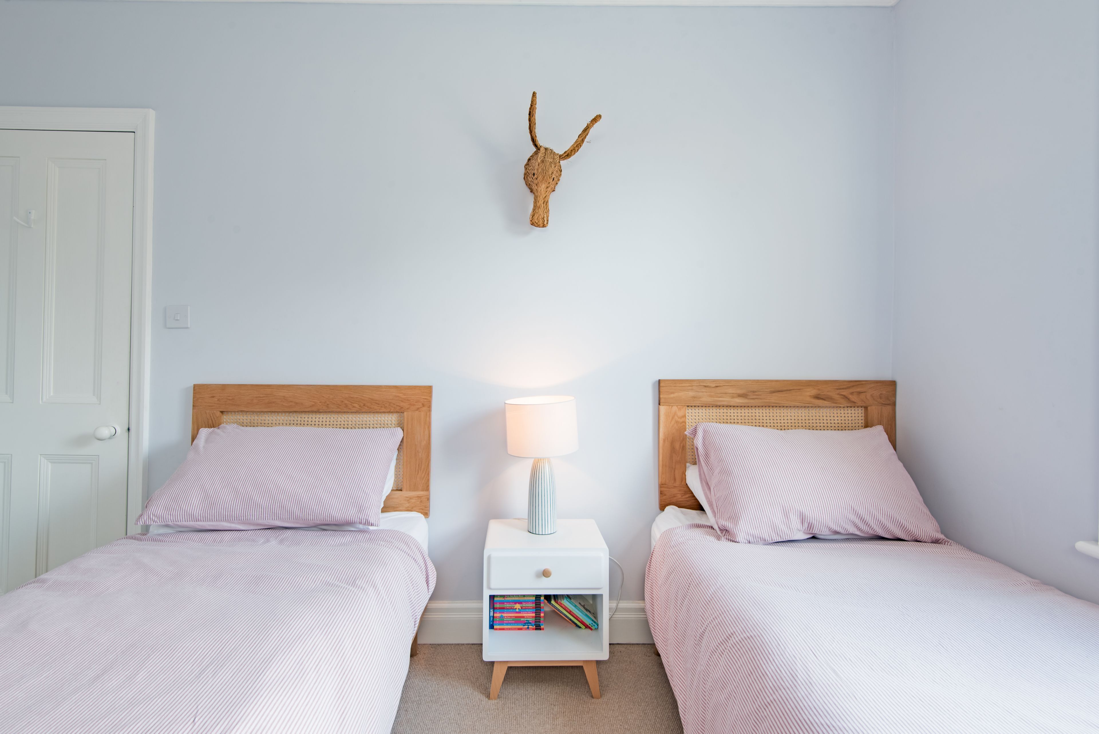 Een slaapkamer met twee bedden, een nachtkastje met een lamp en een dierlijke schedeldecoratie aan de muur.