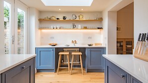 A modern kitchen with blue cabinets, wooden stools, and a skylight. - Liberty Cottage, Broadstairs (Broadstairs)