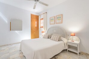 Cozy retreat with a large bed, ceiling fan, and bedside tables with lamps.
