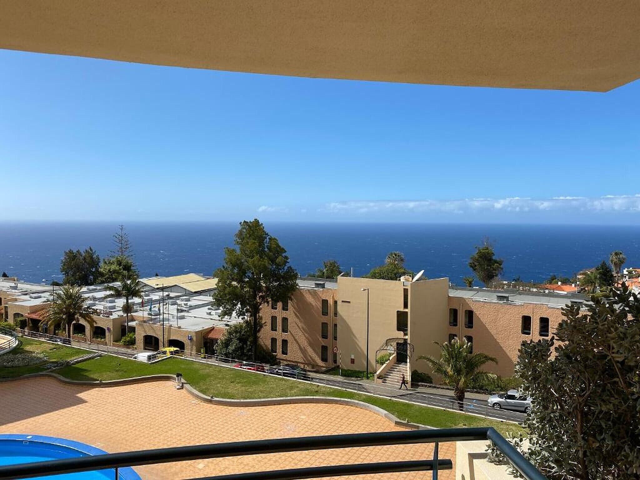 A view of a coastal area with buildings, a swimming pool, and a clear view of the ocean.