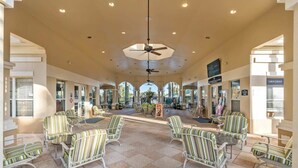 A spacious indoor area with striped chairs and tables, a ceiling fan, and a view of the outside. - Wizarding Retreat: Enchanted Harry Potter Condo (Kissimmee)