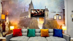 A grey sofa with colorful cushions in front of a large wall mural of a castle. - Wizarding Retreat: Enchanted Harry Potter Condo (Kissimmee)