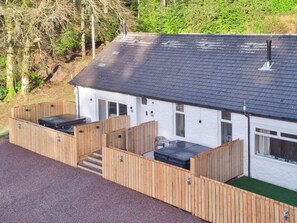 A white building with a dark roof, wooden fences, and a paved driveway. - Elfin Cottage - UK7810 (Near Dunoon)