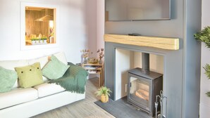 Un salon moderne avec un canapé blanc, une cheminée et un téléviseur fixé au mur.