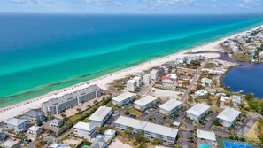 An aerial view of a coastal resort with beachfront properties, a marina, and a swimming pool.