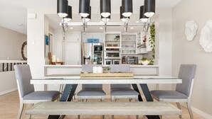 A modern dining area with a white table, four grey chairs, and a bench. There are black pendant lights above the table. - Oceanfront - Ocean Views - Pool  Spa - Pickleball - Walk To All - Renovated (Solana Beach)