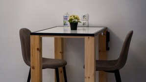 A small table with a black top and wooden legs, accompanied by two chairs with dark fabric seats and backs.