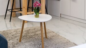 A modern kitchen with white cabinets, a black countertop, and a small dining table with chairs.