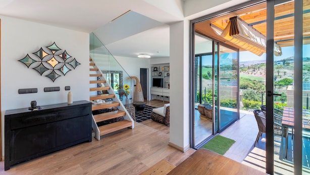 Ein modernes Interieur mit Treppe, einer schwarzen Konsole und Blick auf Pool und Garten.