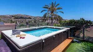 Ein Pool auf dem Dach mit Blick auf einen Hügel und Palmen.