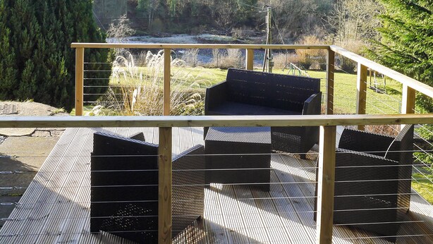 A deck with outdoor seating and a view of a river and forest. - 3 bedroom accommodation in Larkhall (Larkhall)