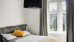 A bed with a grey headboard, white and yellow pillows, and a beige throw blanket. - 3 bedroom accommodation in Larkhall (Larkhall)