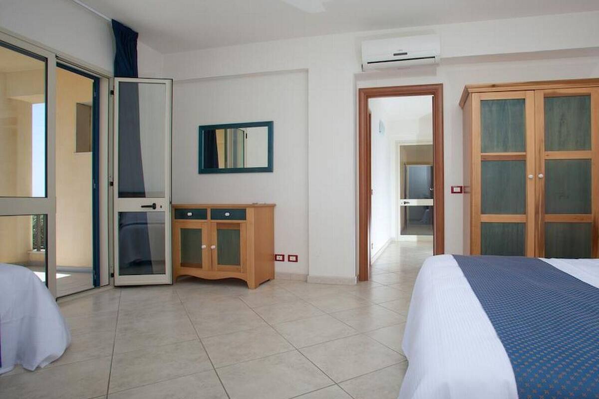 A hotel room with a bed, a desk, a wardrobe, and a mirror.