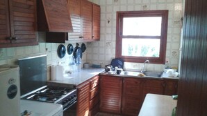 A kitchen with wooden cabinets, a stove, a sink, and a window. - Menorcan house 20 m from the sea (Binisafua)