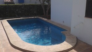 A rectangular swimming pool with a curved edge, surrounded by a tiled deck. - Menorcan house 20 m from the sea (Binisafua)