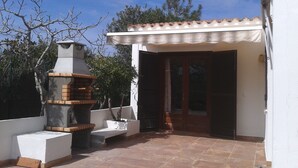 A patio with a brick oven, a white wall, and a door with shutters. - Menorcan house 20 m from the sea (Binisafua)