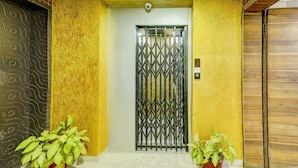 Una puerta con una reja de metal, una cámara de seguridad arriba y dos macetas a cada lado.