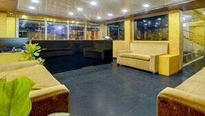 Un vestíbulo con zonas de estar, un mostrador de recepción y ventanas amplias.