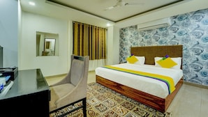 Una habitación de hotel con una cama, un escritorio, una silla, un espejo y una alfombra estampada.