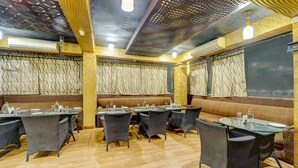 Un interior de restaurante con cabinas y mesas, cortinas estampadas y suelo de madera.