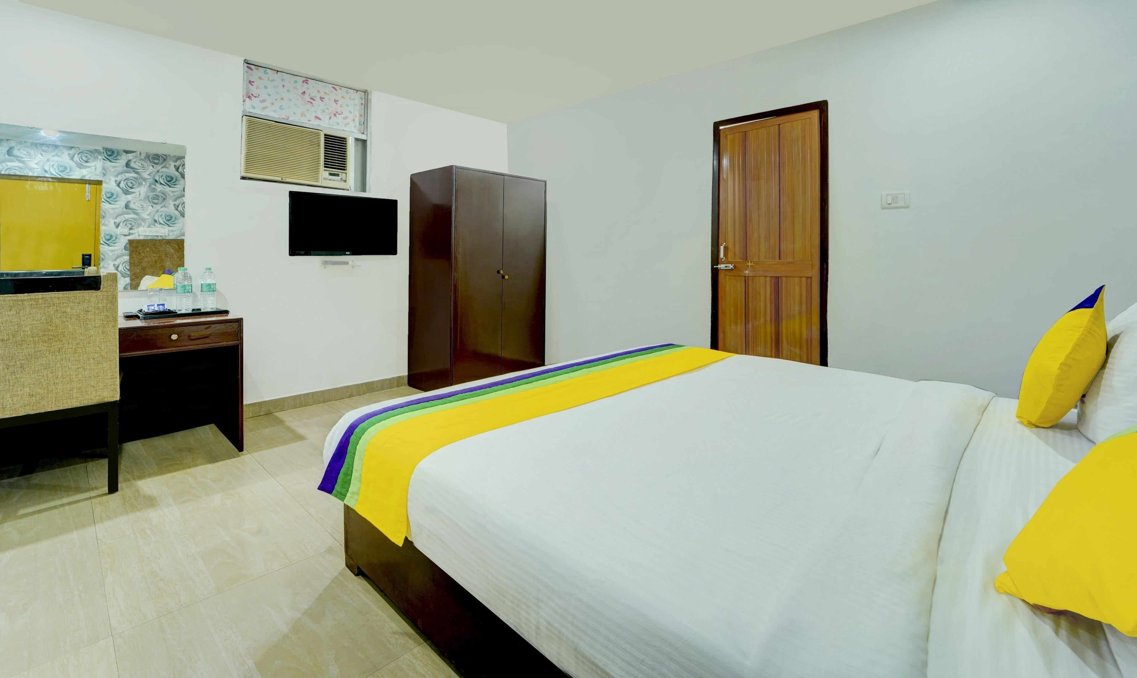 A hotel room with a bed, a desk, a wardrobe, and a television.