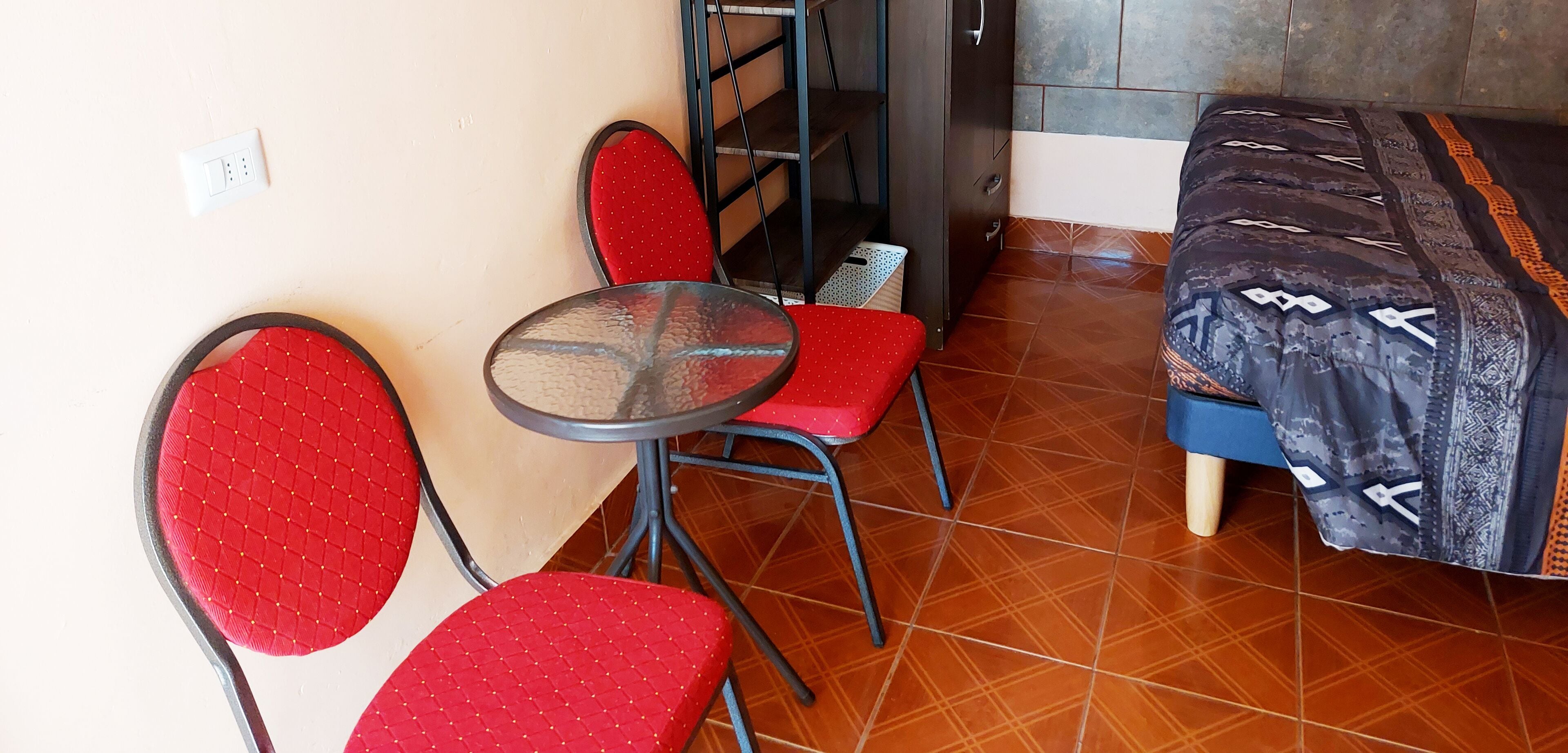 Una habitación pequeña con una cama, una mesa y dos sillas.