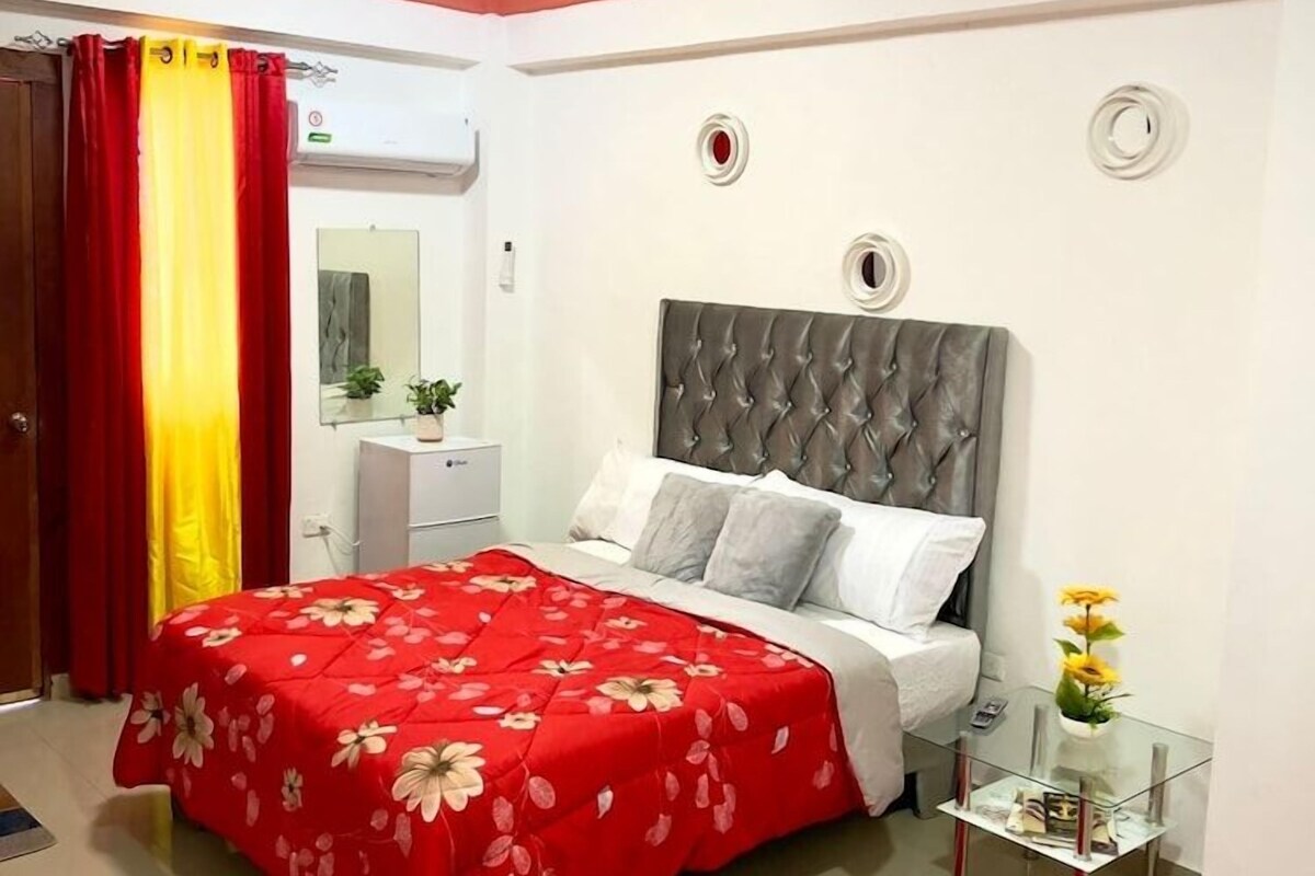 A bedroom with a bed, bedside table, and a red rug.