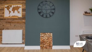 A room with a wooden wall, a world map, a clock, and a log display. - Luke Stays -Good StationCottages (Durham)