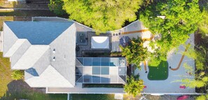 Vue aérienne d’un bâtiment moderne doté d’un toit à la conception géométrique originale, d’une grande façade vitrée et d’une pelouse bien entretenue avec un chemin.