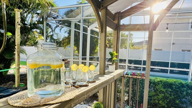 A greenhouse with a wooden bench displaying glass jars and a seashell. - Family friendly activities for all ages! Pool, Golf, Corn-Hole, Fishing & more! (Bradenton)