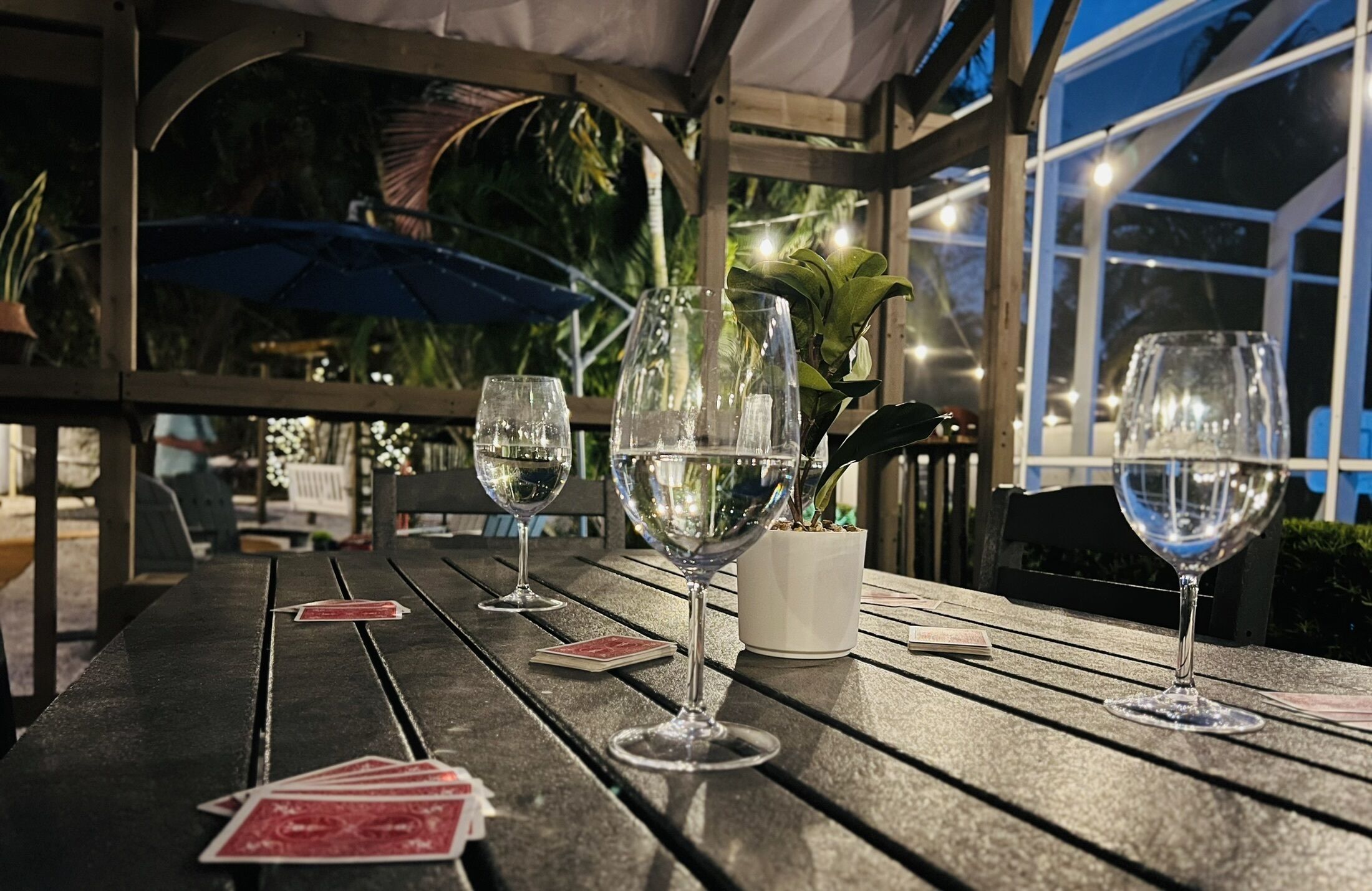 A wooden table with wine glasses and playing cards.
