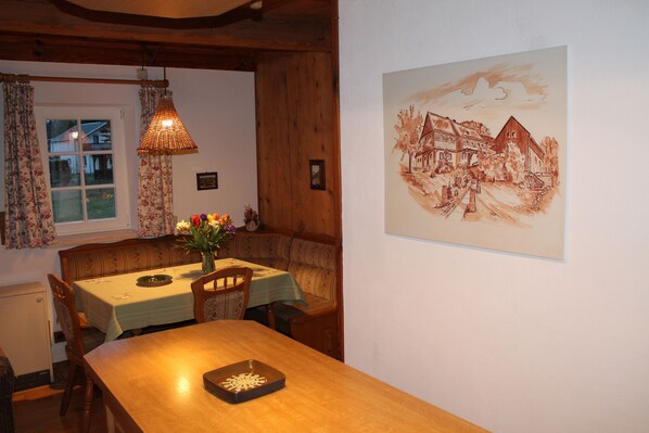 A dining area with a wooden table, chairs, a bench, and a hanging light fixture.