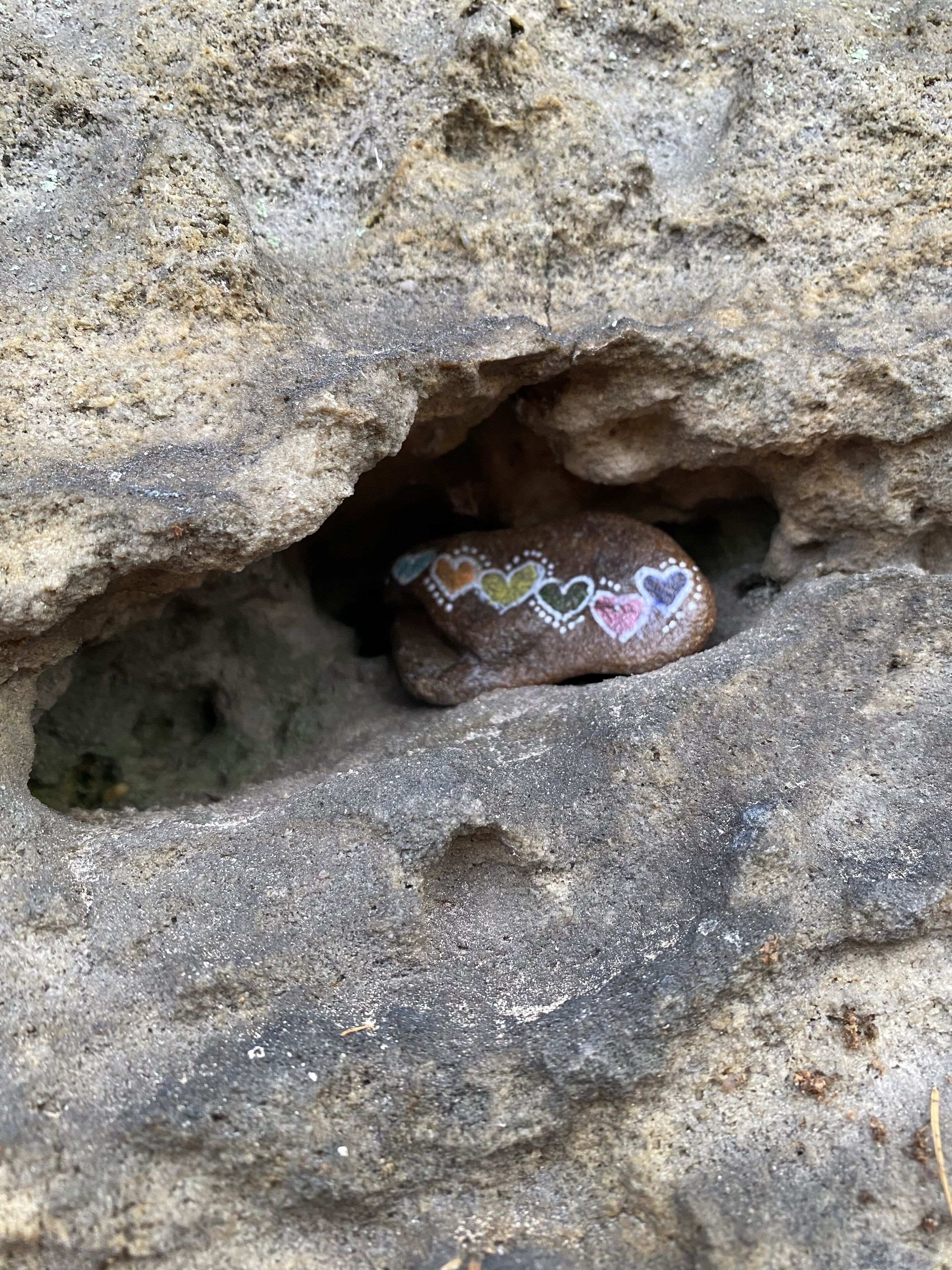 Una roca con un diseño en forma de corazón, parcialmente incrustada en una estructura parecida a una cueva.