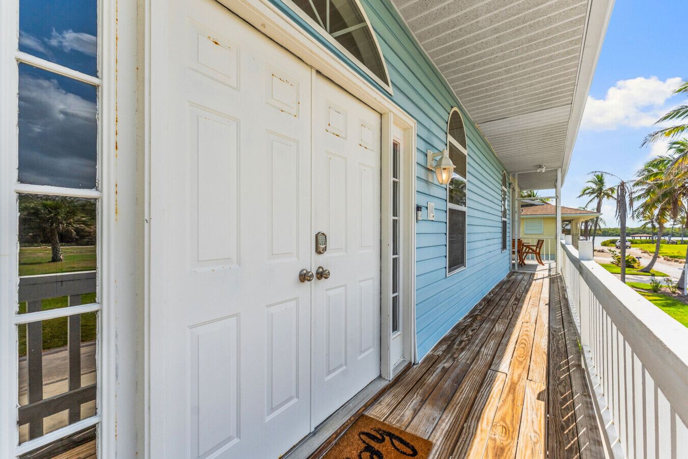 A coastal house with a porch, white doors, and a view of the ocean.