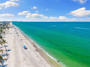 A beach with clear turquoise water, a sandy shore, and palm trees.