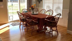A dining area with a wooden table and chairs, a chandelier, and a view through a glass door to the outside.