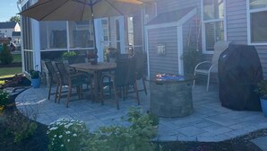 A patio with a table and chairs, a barbecue grill, and a covered area with an umbrella.