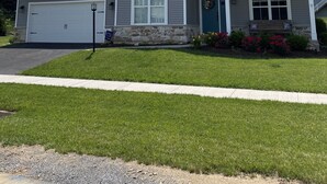 A single-story house with a garage, a front porch with a bench, and a stone foundation.