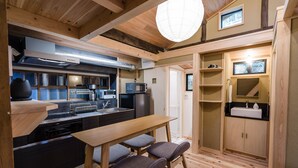 Une cuisine compacte dotée d’appareils électroménagers modernes, un coin repas avec des tabourets et un plafond en bois.