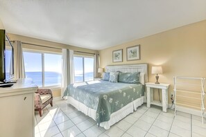 A bedroom with a bed, a desk, a chair, a bedside table with a lamp, a window with curtains, and a wall-mounted drying rack. - Outstanding 2 bedroom / 2 bath gulf front condo (Orange Beach)