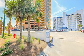 A hotel with a parking lot, palm trees, and a building with balconies. - Outstanding 2 bedroom / 2 bath gulf front condo (Orange Beach)